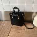 Glossy black retro handbag with gold studs and cross-body strap on wooden surface - Black