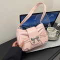 Borsa a spalla plissettata rosa con fibbia a fiocco in metallo su una scrivania - Rosa