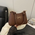 Dark brown leather shoulder bag featuring a golden bow detail and knotted strap design - Brown