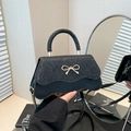Black sequined crossbody bag with a golden bow detail and elegant curved wave bottom - Black