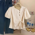 Beige blouse met pofmouwen, zijknoppen en strik in de taille getoond op een mannequin - S / Abrikoos