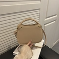 Minimalistische beige Umhängetasche mit Tragegriff auf weißen Büchern in hellem Ambiente - Khaki