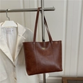Grande borsa tote marrone con scritte dorate mostrata in un elegante contesto moda - Marrone