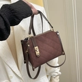 Quilted dark brown crossbody bag with gold twist lock and crossbody strap shown held - Brown