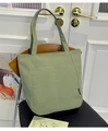 Bolso tote verde claro minimalista con bolsillo frontal y asas largas en silla de madera - Verde