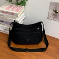 Versatile black nylon crossbody bag with multi-pocket storage on wooden surface - Black