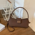 Dunkelbraune Baguette-Tasche mit Metallschnalle auf einem eleganten Holztisch - Braun
