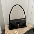 Chic black polished shoulder bag with golden capsule clasp on a beige fuzzy scarf - Black