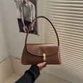 Close-up of vintage brown baguette bag with gold oval clasp and smooth leather finish - Tan
