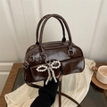 Deep brown glossy handbag with a large pearl bow charm and adjustable shoulder strap - Brown