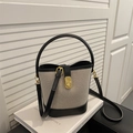 Sac seau rétro bicolore avec poignée incurvée et fermoir doré sur support minimaliste - Noir