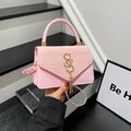 Rosa Handtasche mit Webstruktur, goldenem Logo und Quaste auf modernem Hintergrund - Rosa
