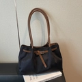 Elegante borsa tote nera con spalline marroni e fibbia in metallo in un ambiente reale - Nero