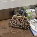 Close-up of leopard print shell bag with gold engraved metal frame and ring handle - Brown
