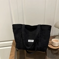 Zwarte corduroy shopper voor dames met een minimalistisch wit merklabel op tafel - Zwart