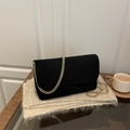 Elegant black faux suede flap bag with chunky gold chain strap on a glass surface - Black