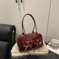 Deep burgundy patent leather bowling bag with pockets and bows on a cozy background - Red