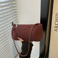 Minimalist burgundy suede baguette bag with zipper closure held by a model - Red