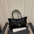 Glänzende schwarze Ledershopper mit goldener Schnalle auf modernem Sessel - Schwarz