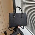 Detail of black tote bag featuring cross-grain texture and premium gold hardware - Black