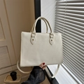 Close-up of cream tote bag with Saffiano texture and golden hardware studs - White