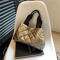 Detail of champagne gold quilted tote bag with black canvas handles on a modern chair - Champagne
