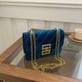 Navy blue velvet quilted chain bag with gold interlocking buckle on wooden table - Blue