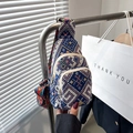 Detailed view of woven crossbody bag showing three zipper pockets and geometric strap - Blue