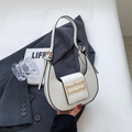 Close-up of white crescent shoulder bag with golden geometric clasp on grey blazer - White