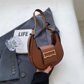 Detalle del bolso hobo de cuero marrón con hebilla dorada sobre una chaqueta gris - Marrón