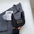 Details einer schwarzen Halbmond-Tasche mit goldener Schnalle auf grauem Anzug - Lila
