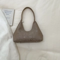 Detail view of brown half-moon bag featuring vertical ribbed texture and protective metal feet - Khaki
