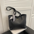 Bolso tote negro minimalista con pañuelo de seda estampado, colocado sobre libros - Negro