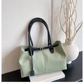 Détail du sac cabas vert clair avec anses noires et boucle dorée sur décor blanc - Vert