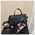 Detalle de un bolso de cuero negro con solapa curva y elegantes hebillas magnéticas - Negro
