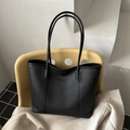 Retro black leather tote bag with lychee texture and dual straps on a designer chair - Black