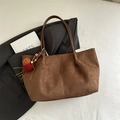 Braune Shopper-Tasche aus Wildleder-Imitat mit Quasten-Anhänger auf grauem Blazer - Braun mit Anhänger