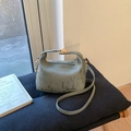 Detailansicht der graugrünen Handtasche mit Textur, goldenem Drehverschluss und Riemen - Grün