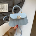 Detail of light blue crossbody bag featuring woven V-pattern texture and gold M logo buckle - Blue
