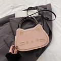 Pink cat-shaped tote bag with embroidery details and brown handles on a cozy bed - Pink