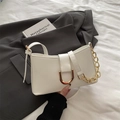 White minimalist baguette bag with golden U-shaped buckle and chain strap on bed sheet - White