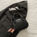 Bolso bandolera pequeño negro clásico con asas dobles y letras doradas sobre chaqueta - Negro