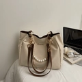 Borsa tote beige con manici marroni e catena di perle su una scrivania moderna - Bianco Sporco