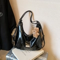Glossy black tote bag with plush puppy pendant displayed on a metal suitcase - With Pendant / Black
