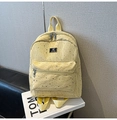 Detail of yellow canvas backpack showing silver star prints and metal zipper texture - Yellow