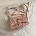 Pink crossbody bag with M-letter print, silver chain, and buckle on a beige blazer - Pink