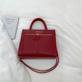 Detalle de bolso rojo de cuero sintético con textura de espiga y logo dorado - Sin colgante / Rojo
