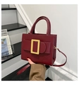 Detalle del bolso de cuero burdeos con hebilla dorada grande y correa de hombro ajustable - Rojo