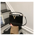 Detail of black leather and suede bucket bag with gold V-buckle and elegant handle - Black