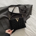 Elegante borsa a mano leopardata nera con fibbia a V dorata su abito grigio - Nero